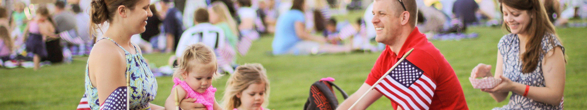 Family Sitting in Field with American Flags