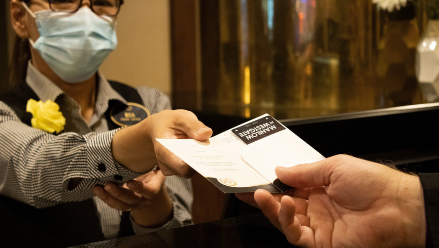 Tenemos su seguridad | El personal de recepción entrega el folleto de bienvenida a los huéspedes