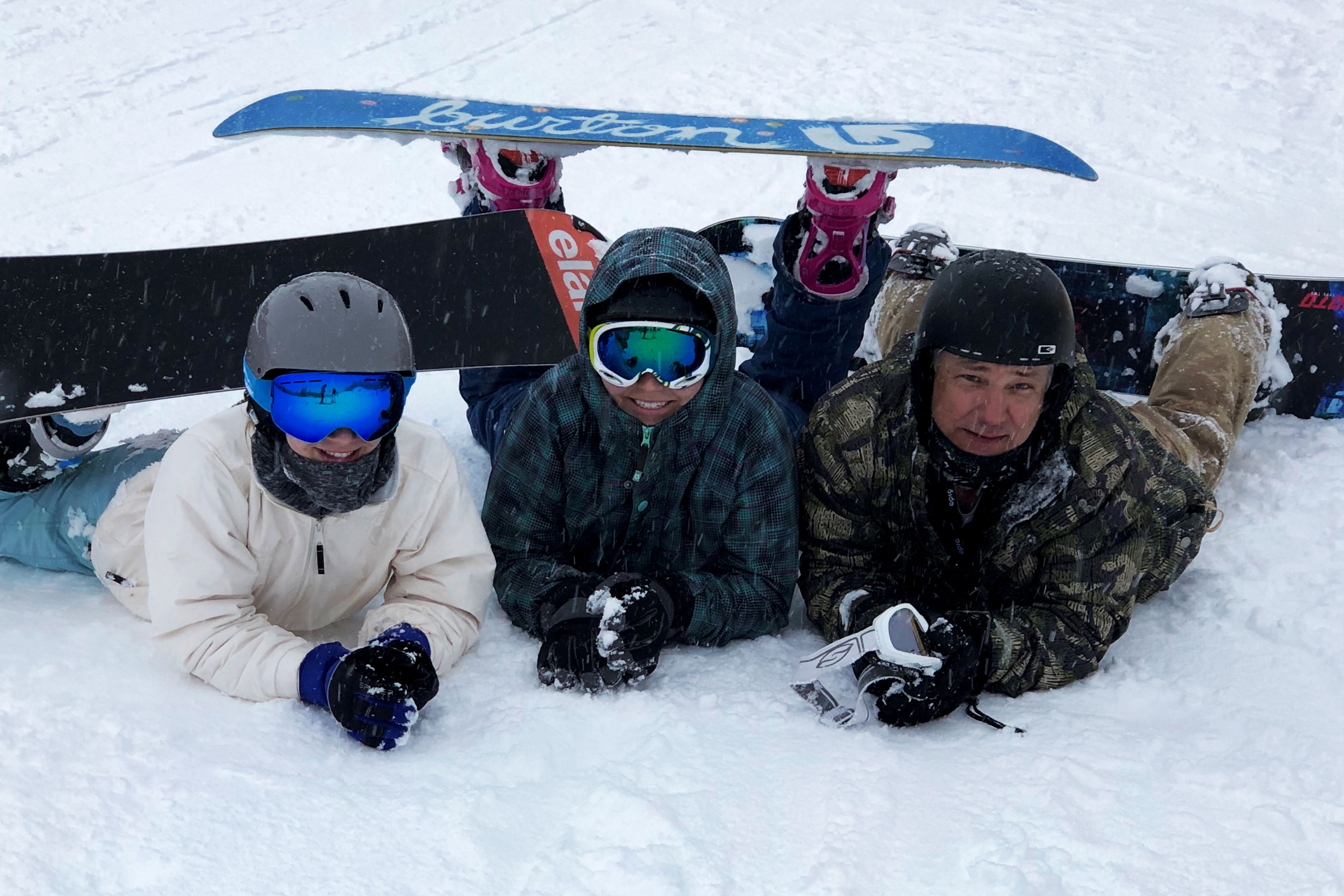 Family posing for a picture with skii gear on a snowy mountain
