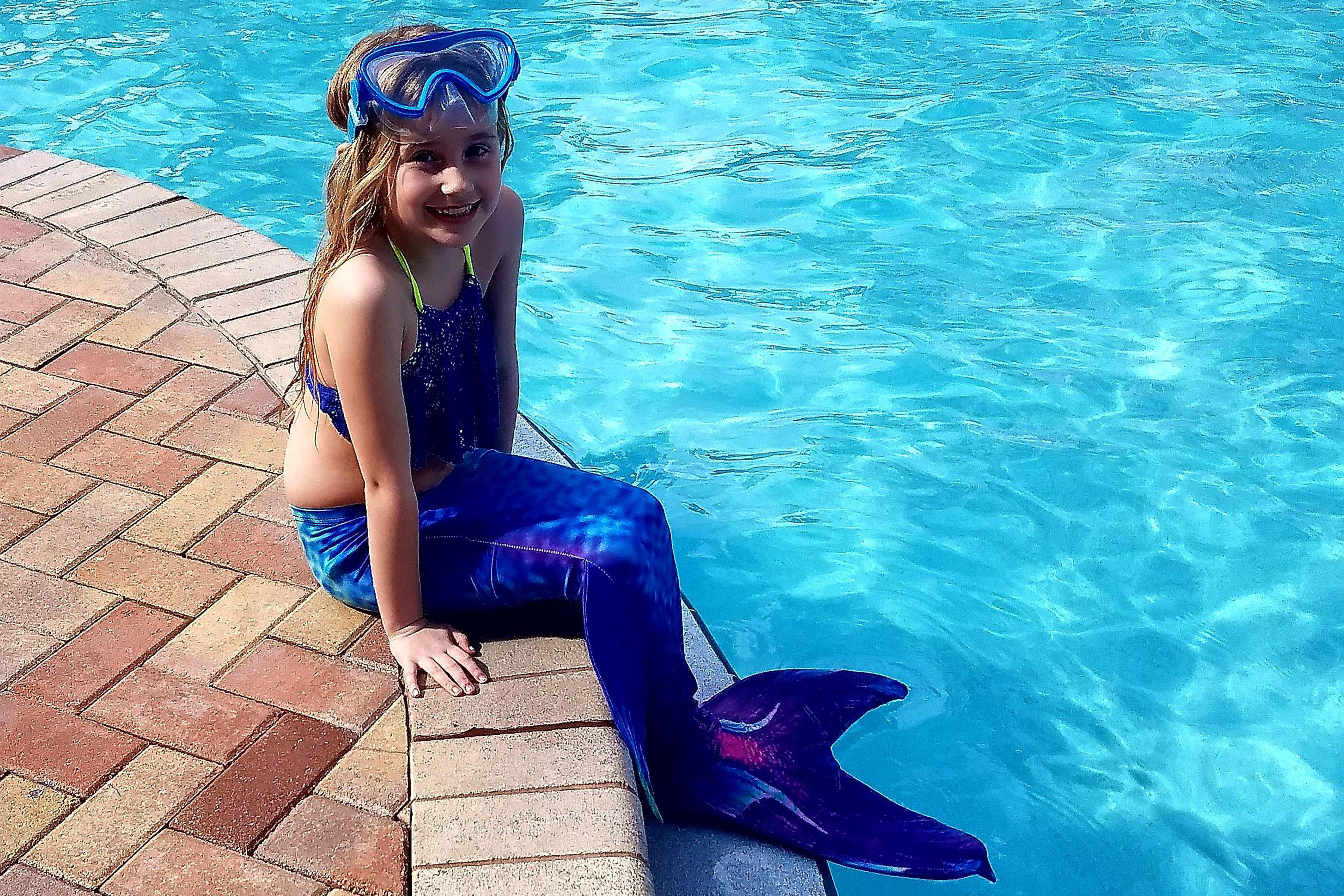 A little girl dressed as mermaid sitting by the pool - Westgate Town Center Resort